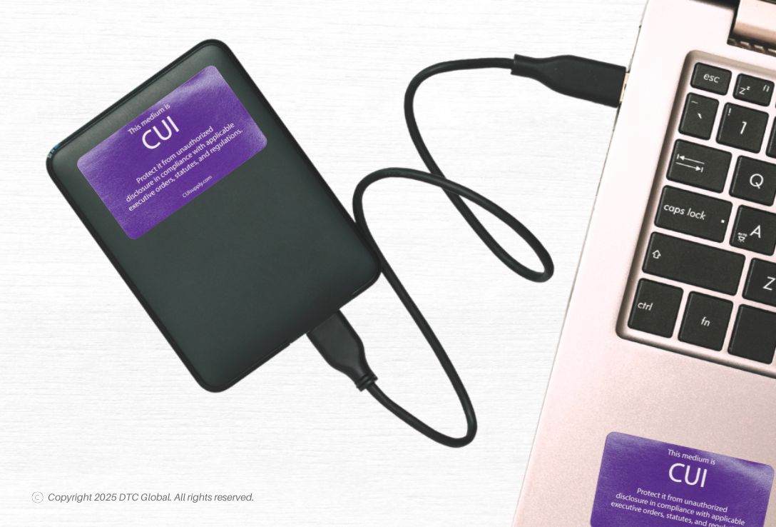 External hard drive with purple Generic 905 - CUI Digital Media Label without Government Property next to a laptop keyboard with a similar label